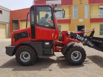 Trator vermelho de carregamento estacionado num pátio